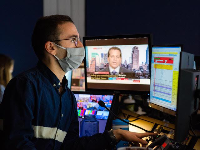 Leo Sands, wearing a face mask, working at multiple computer screens